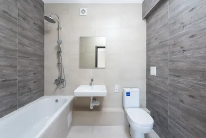 Bathtub, shower fixtures, wall-hung sink and toilet in a tiled bathroom